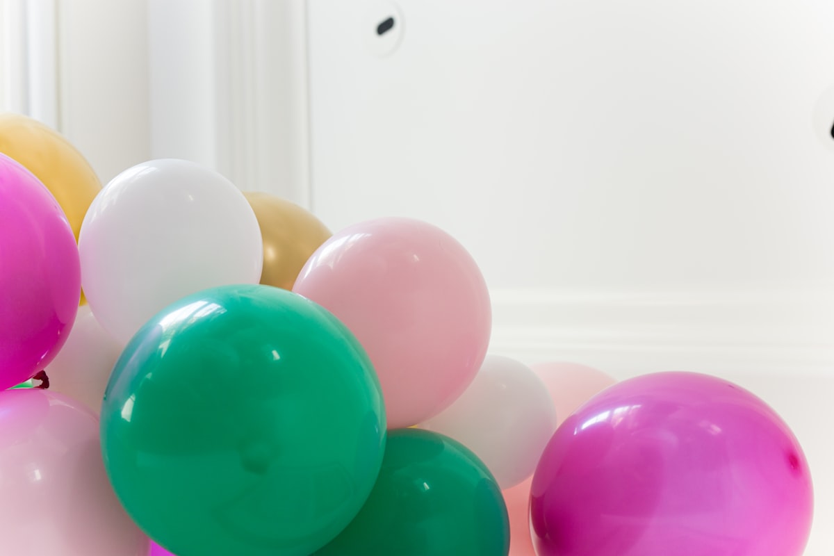 Purple and pink balloon bouquet arrangement on white wall